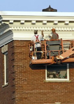 workers painting exterior of building on lift