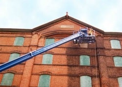 worker on lift painting exterior of building