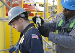 worker connecting safety gear to another worker for industrial painting job