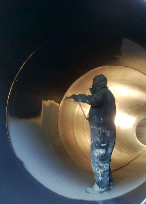 worker spray painting industrial tube