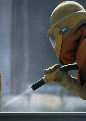 worker in protective gear power washing in preparation for an industrial painting job