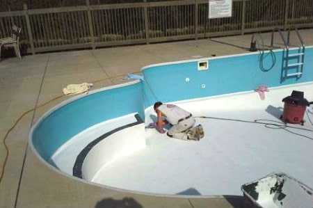 A Modern Painting worker detailing pool paint on a residential pool.