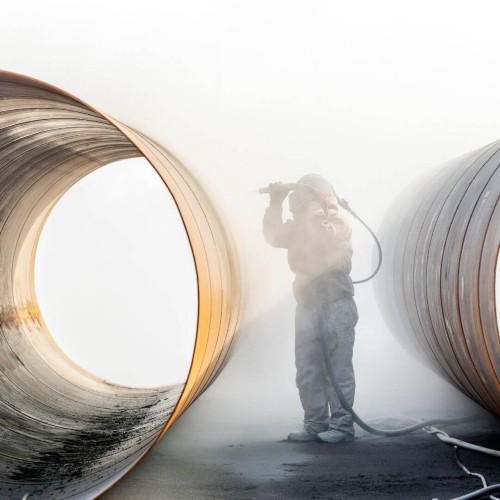 Worker in protective gear using blasting service