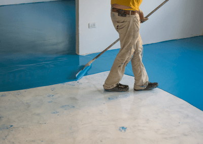 an employee applying a blue epoxy floor