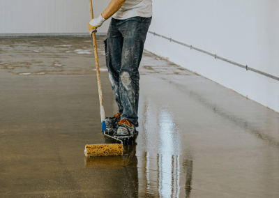 employee applying epoxy floor in a basement