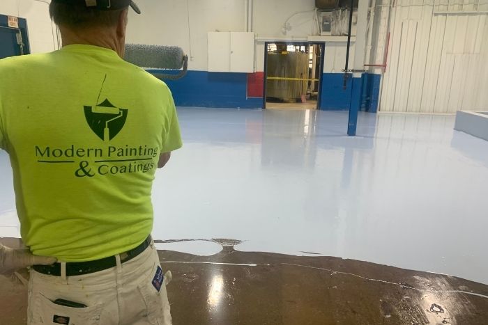 commercial epoxy an employee overseeing the pouring of epoxy floor coating in a warehouse commercial building