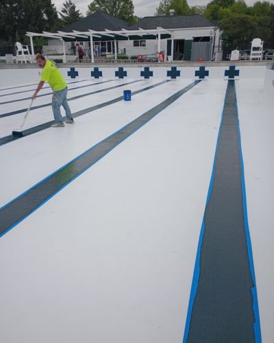 2 a Modern Painting worker rolling on navy stripes onto the bottom of a freshly painted public pool