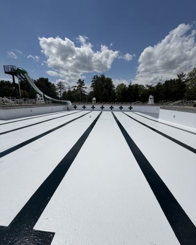 3 a Modern Painting worker rolling on navy stripes onto the bottom of a freshly painted public pool